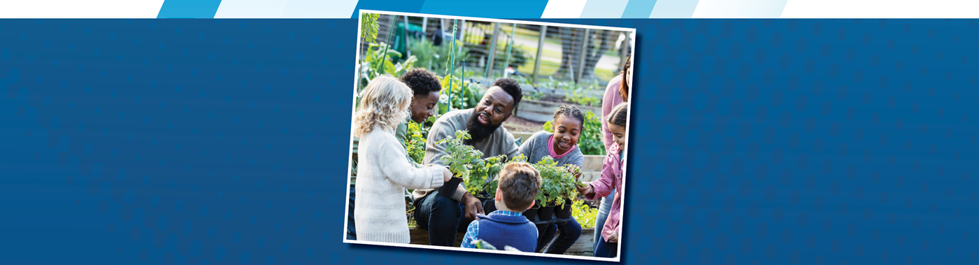 A teacher and a group of young elementary students having class at a garden