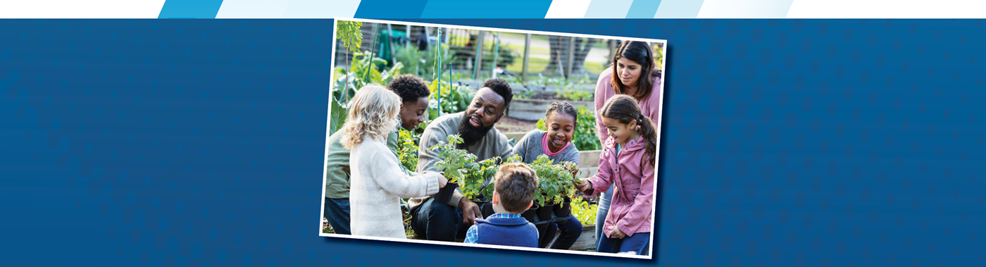 A teacher works with a group of students in a garden
