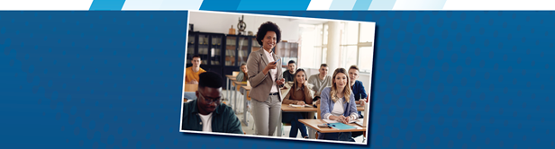 A teacher faces the camera in a full classroom.