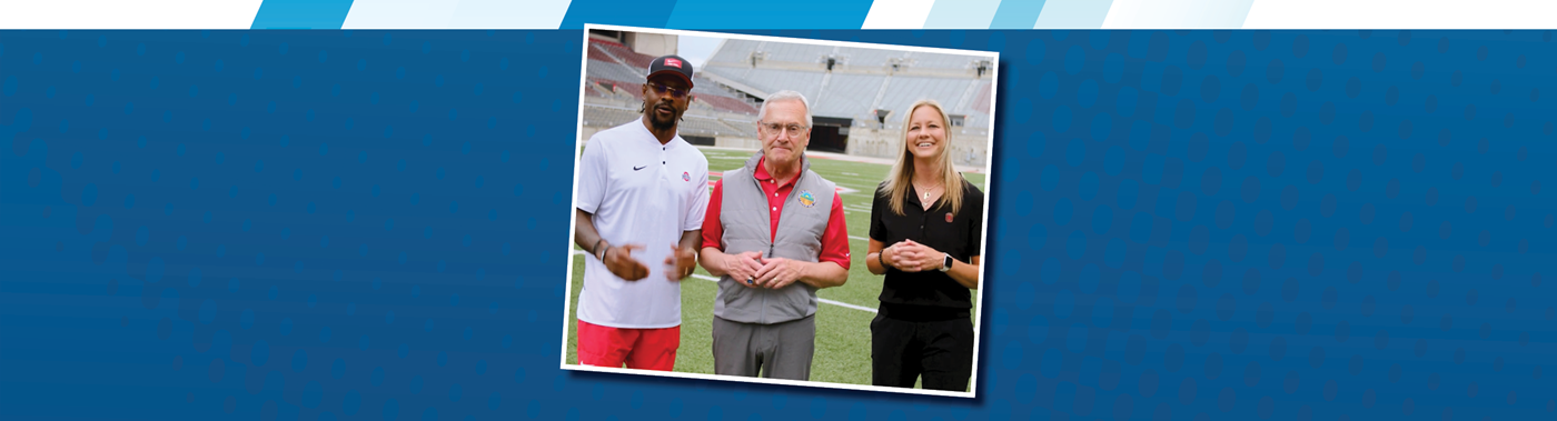Coach Tressal standing with two colleagues on a football field.