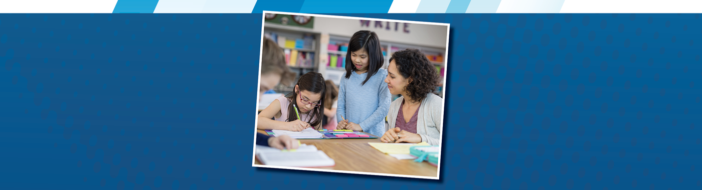 teacher working with two elementary students at a table