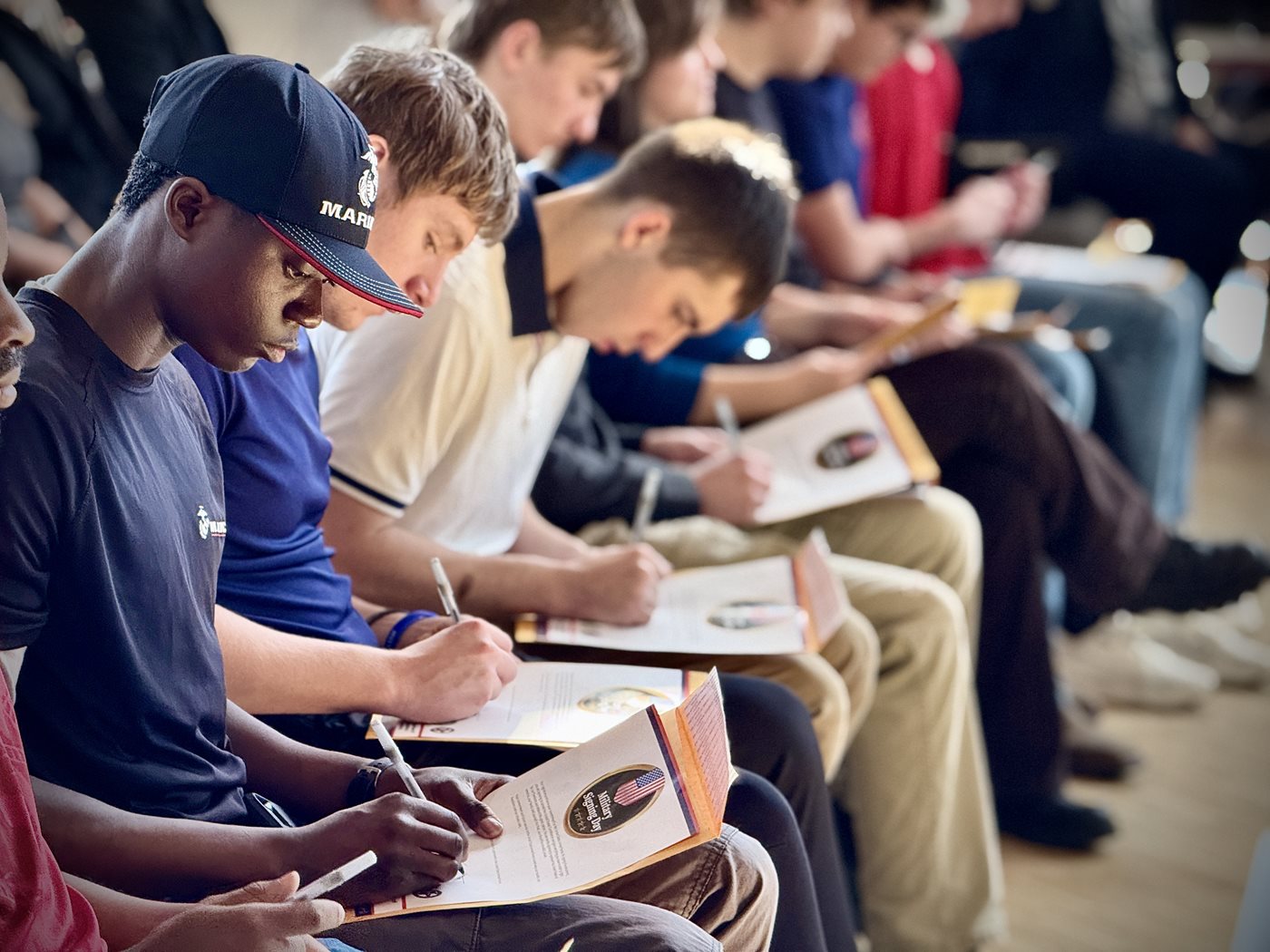 A group of students sign a document during Military Signing Day
