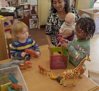 preschool teacher doing classroom activites with a baby and two toddlers