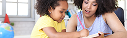 a parent working with a young child who is writing