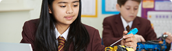 Two middle school students wearing uniforms who are working on a science experiement