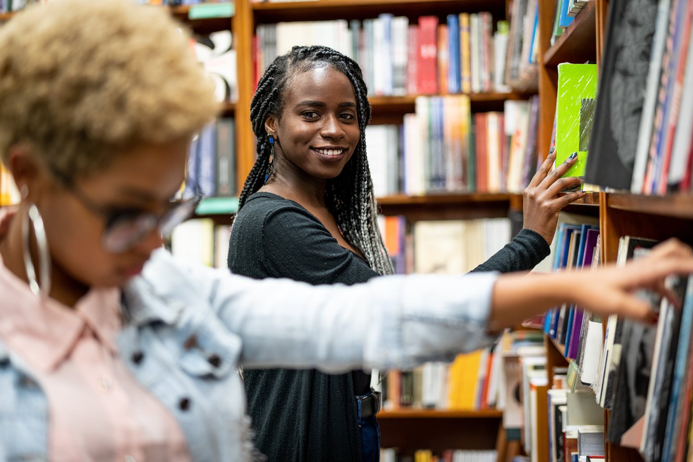 Two women looking for books in library