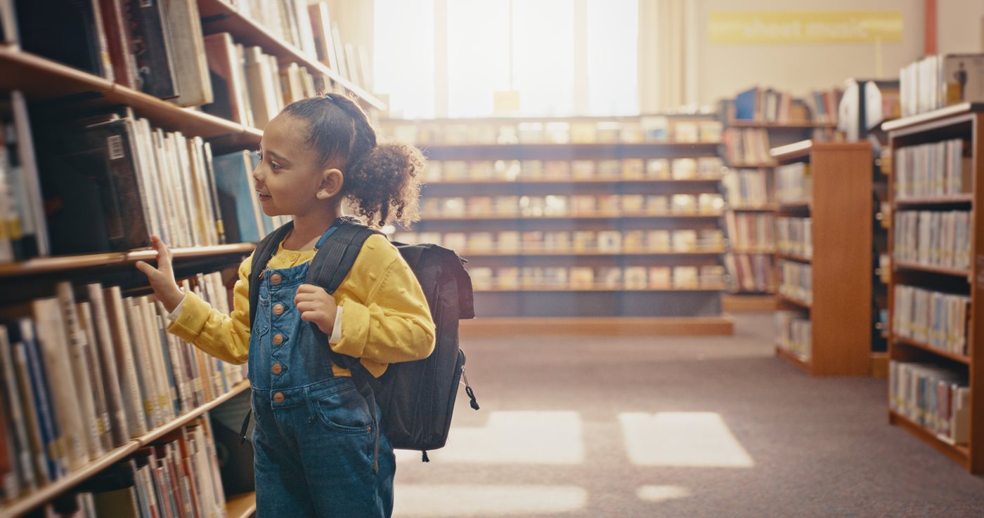 Young girl in library choosing book