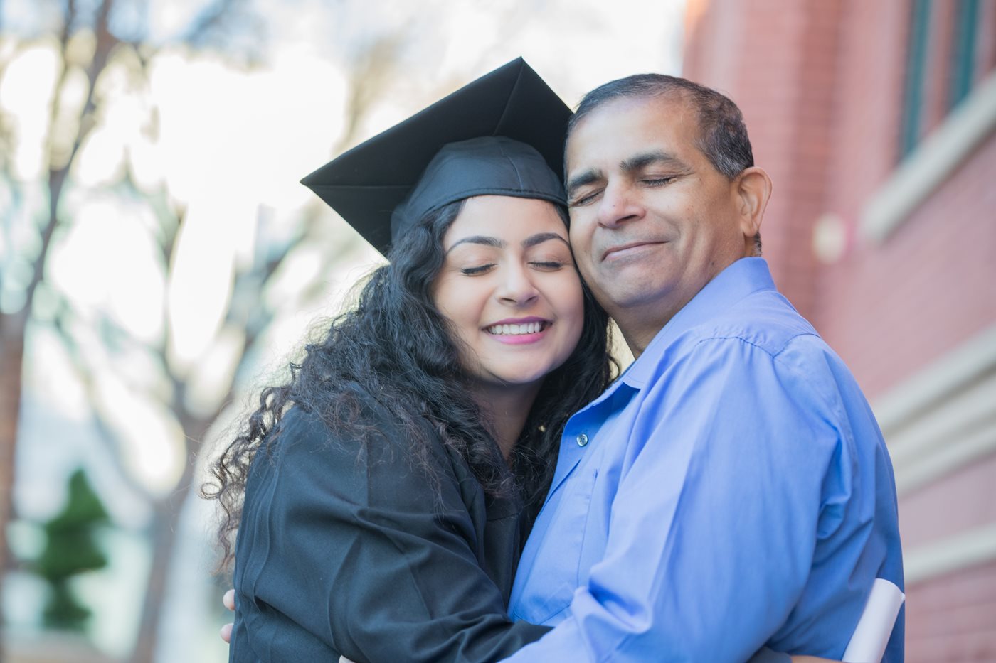 Father hugging graduating daughter